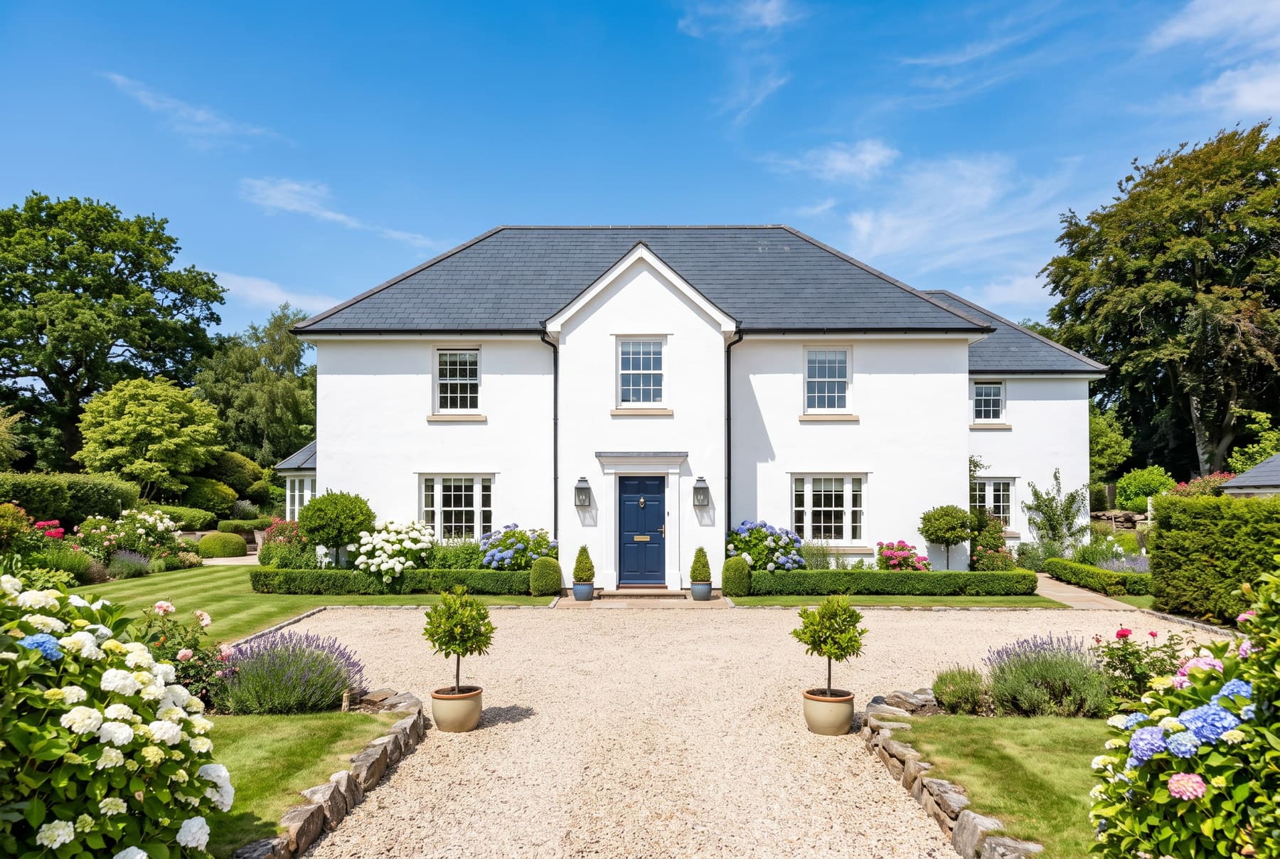 Devon house exterior after softwashing with spotless white render, clean slate roof and gravel drive