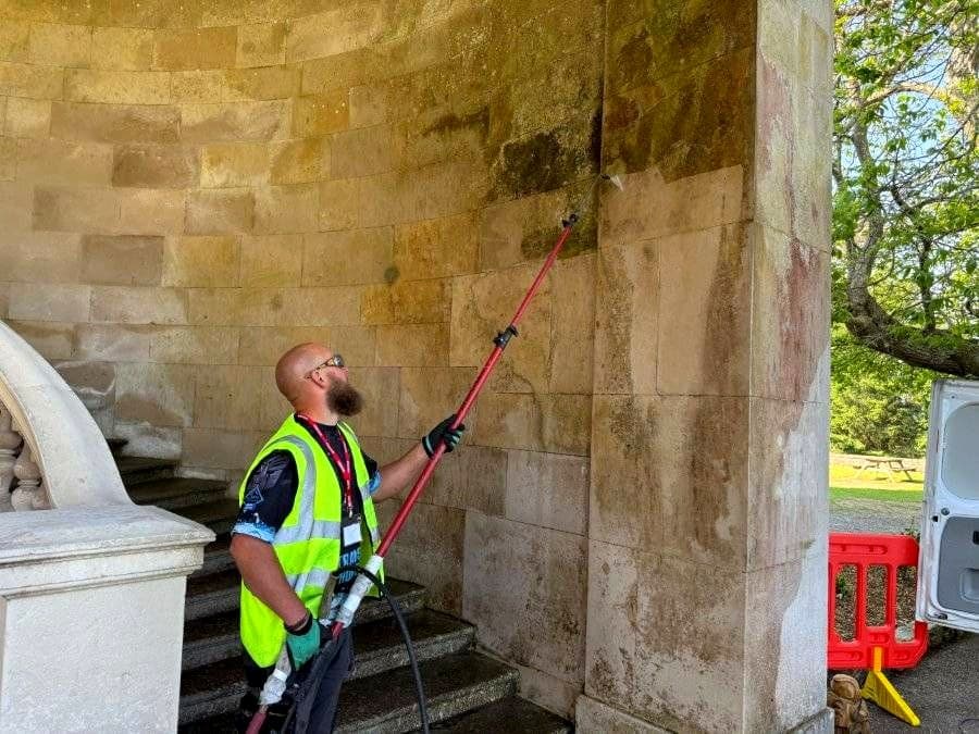 Technician steam cleaning heritage stone pillars on a listed Devon building